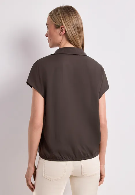 Chemisier à col chemise et ourlet élastiqué espresso brown Femme de dos portant une chemise marron à manches courtes et un pantalon clair.