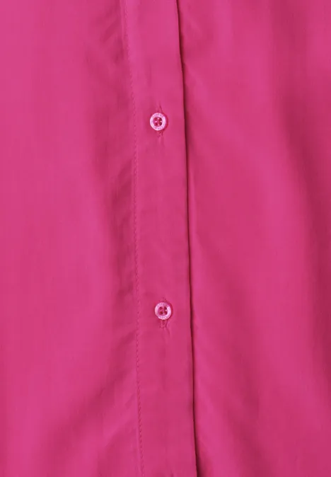 Nahaufnahme einer pinken Bluse mit weißen Knöpfen und Knopfleiste.