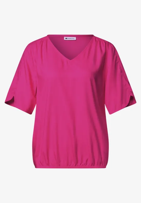 Ein pinkfarbenes Damen-Shirt mit V-Ausschnitt, halblangen Ärmeln und elastischem Saum.