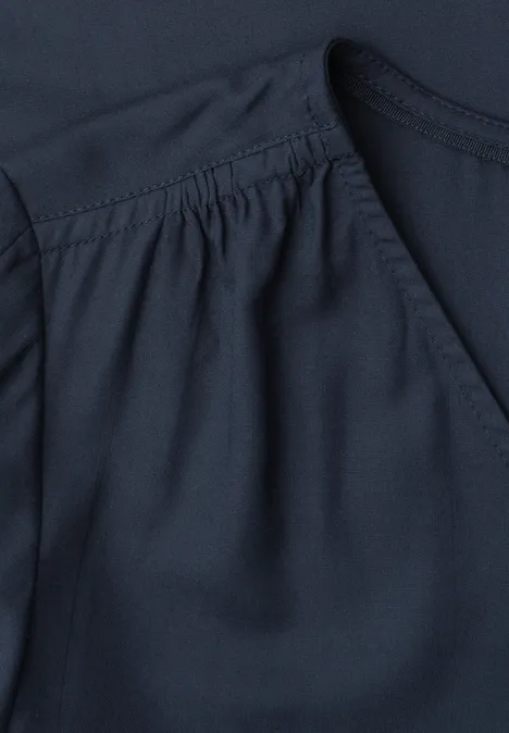 Nahaufnahme eines dunkelblauen Kleidungsstücks mit Falten am Ärmelansatz.
