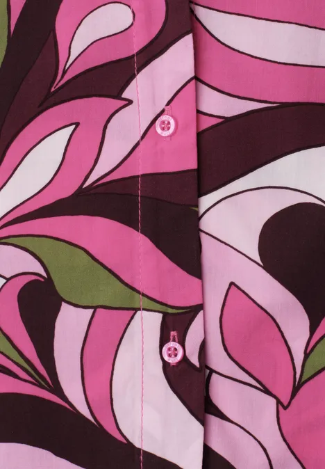 Stoff mit rosa-weißen und braun-grünen, abstrakten floralen Mustern und sichtbaren Knöpfen.