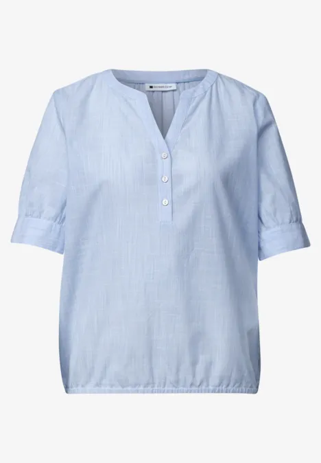 Blouse bleu clair à manches mi-longues, patte de boutonnage courte et ourlet élastiqué.