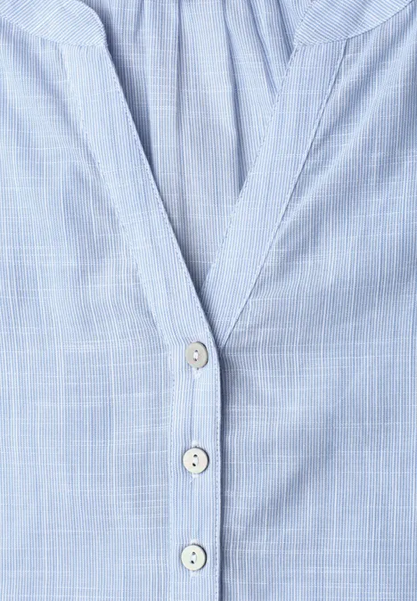 Chemise bleu clair à motif quadrillé fin et trois boutons apparents.