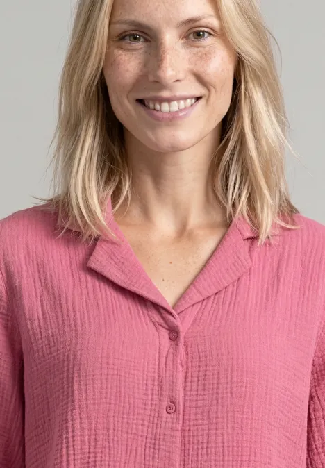 Mousselineblouse met bowlingkraag blush berry Eine lächelnde Frau mit blondem Haar trägt eine rosa, strukturierte Bluse.