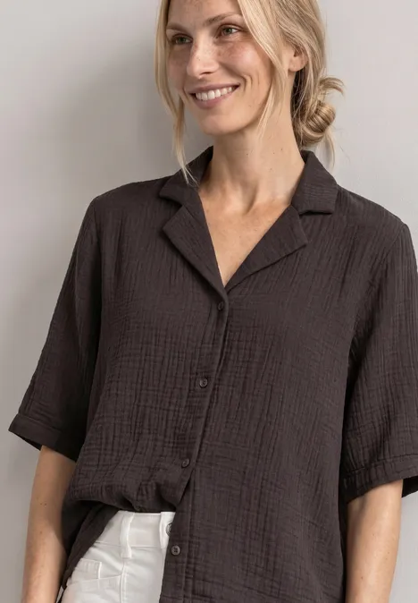 Mousselineblouse met bowlingkraag black coffee Lächelnde Frau in locker geschnittenem, schwarz texturiertem Hemd und weißer Hose.