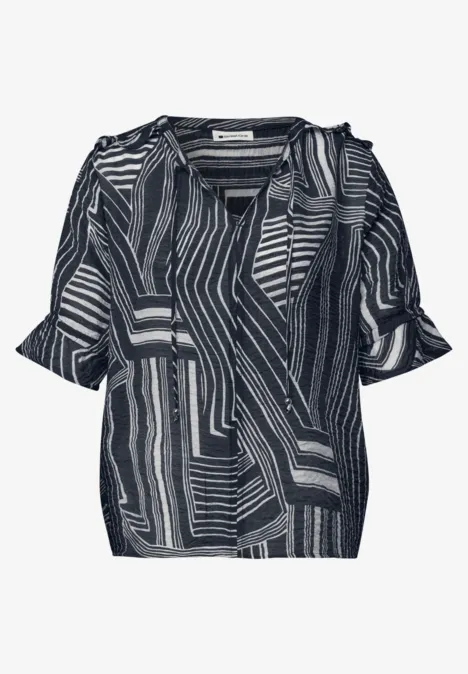 Schwarz-weiße Damenbluse mit V-Ausschnitt, kurzen Ärmeln und abstraktem Geometriemuster.