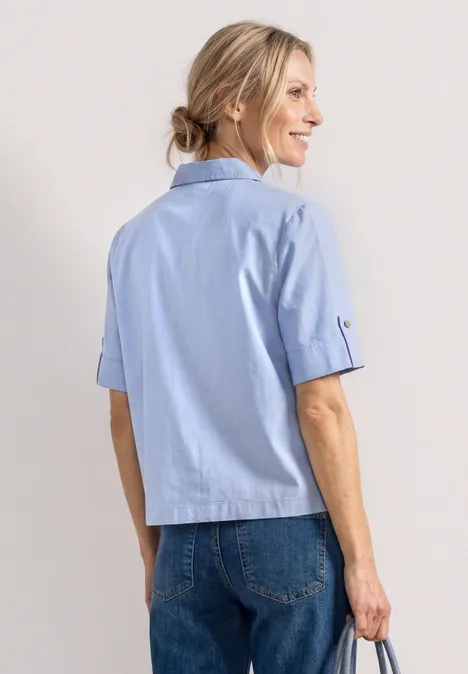 Chemisier à manches courtes en chambray avec col chemise original blue Vue de dos d'une femme portant une chemise bleu clair à manches courtes et un jean bleu sur fond blanc.