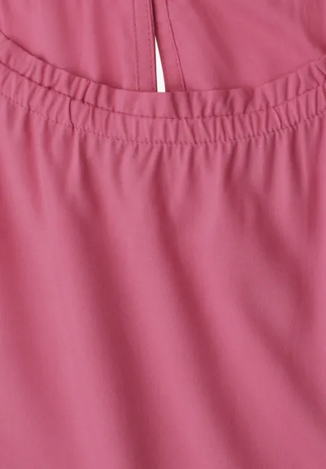 Nahaufnahme eines rosa Kleidungsstücks mit elastischem Ausschnitt und zierlicher Mittelnaht.