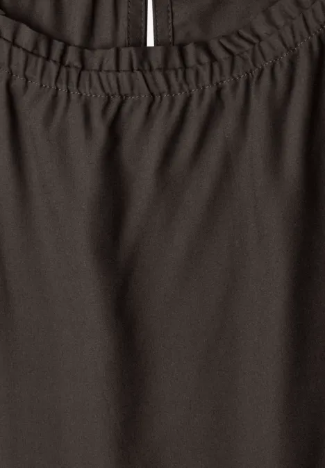 Nahaufnahme eines dunklen Kleidungsstücks mit elastischem Bund und seitlichem Schlitz.
