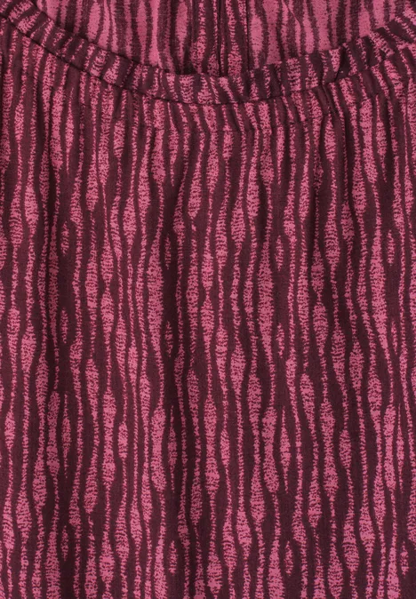 Gros plan d’un vêtement à motif ondulé rose foncé et noir, texture douce et léger froncé sur l'encolure.