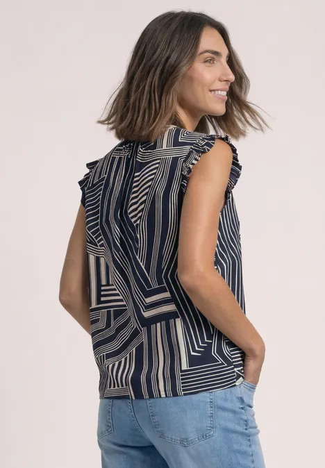 Vrouw lachtend in een mouwloze top met marineblauw-beige strepen, volantmouwen en zakken, handen in jeans.