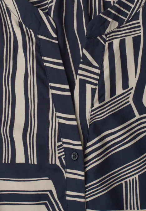 Close-up van een kledingstuk met marineblauwe en crèmekleurige geometrische strepen.