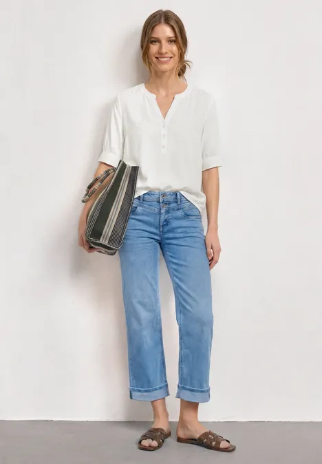 Blouse met korte mouwen, split in de hals en elastische zoom off white Iemand draagt een wit overhemd, een blauwe spijkerbroek en sandalen en houdt nonchalant een tas vast.