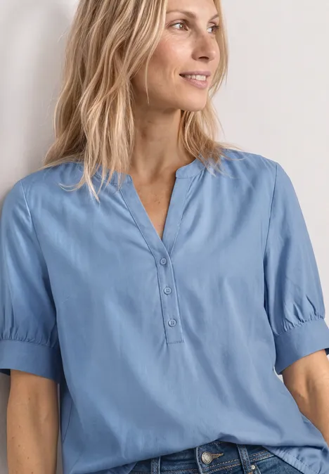 Blouse met korte mouwen, split in de hals en elastische zoom northern blue Vrouw in lichtblauw bloesje met korte mouwen, V-hals en knoopsluiting, ontspannen pose.