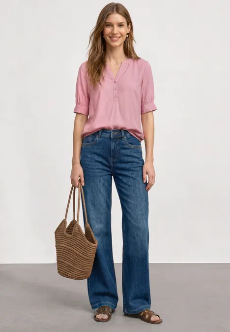 Blouse met korte mouwen, split in de hals en elastische zoom vintage blush Vrouw in roze blouse, blauwe jeans, sandalen en gevlochten tas voor een neutrale achtergrond.