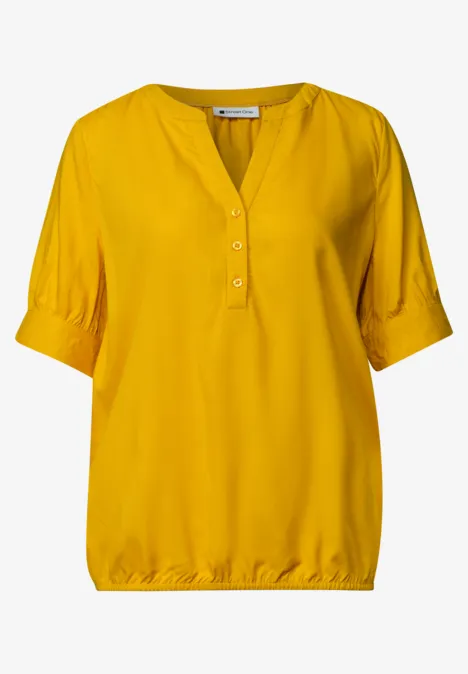 Blouse met korte mouwen, split in de hals en elastische zoom saffron yellow Gele damesblouse met driekwartmouwen en halve knoopsluiting bij de hals.