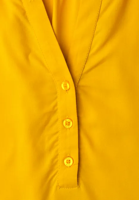 Blouse met korte mouwen, split in de hals en elastische zoom saffron yellow Geel bovenstuk met V-hals en drie gele knopen in het midden.