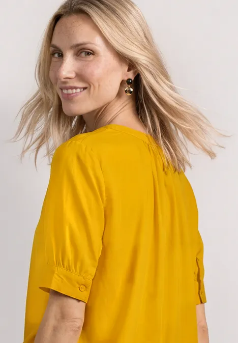 Blouse met korte mouwen, split in de hals en elastische zoom saffron yellow Vrouw met blond haar draagt geel shirt met halflange mouwen, zijaanzicht.