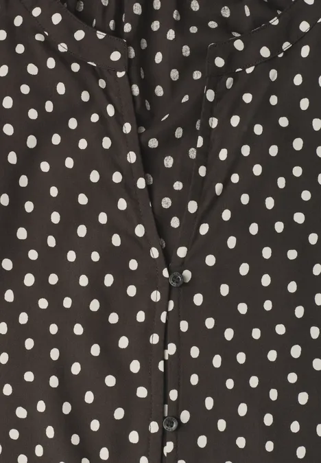 Schwarze Bluse mit weißen Punkten.