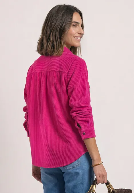 Corduroy overhemd met lange mouwen en knopen magenta dream Frau im leuchtend pinken Cord-Hemd, blaue Jeans, Blick über die Schulter, trägt eine braune Tasche.