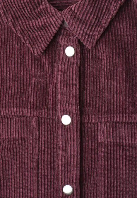 Corduroy overhemd met lange mouwen en knopen rustic rouge Nahaufnahme einer weinroten Cordjacke mit Struktur, Hemdkrause und weißen Druckknöpfen.