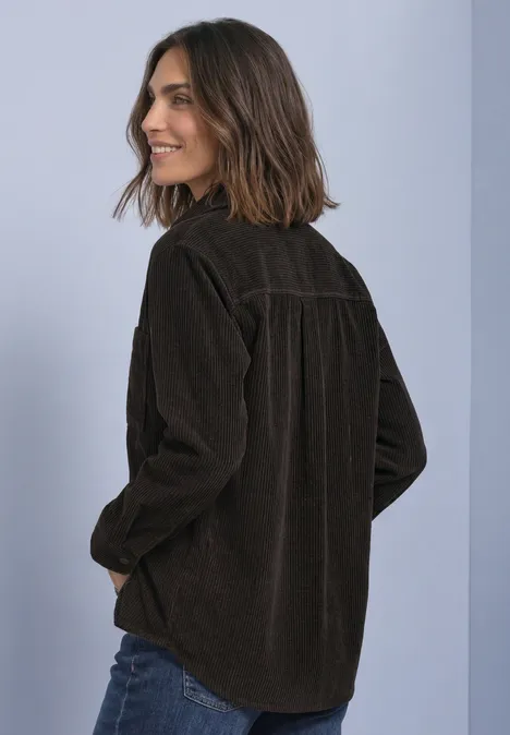 Corduroy overhemd met lange mouwen en knopen black coffee Frau mit schulterlangem Haar trägt eine dunkelbraune Cordjacke vor hellblauem Hintergrund.