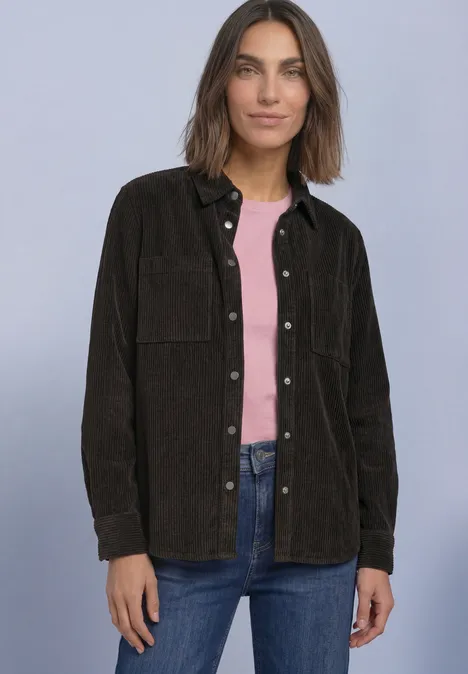 Corduroy overhemd met lange mouwen en knopen black coffee Frau vor neutralem Hintergrund trägt braune Cord-Überhemdjacke, rosa Top und Jeans.