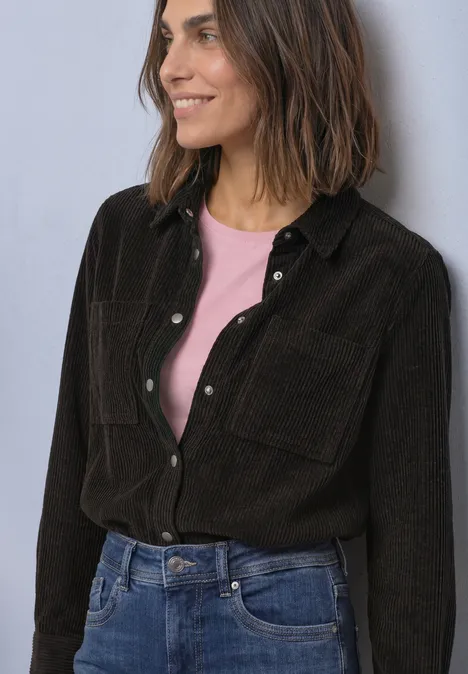 Corduroy overhemd met lange mouwen en knopen black coffee Frau in schwarzem Cordhemd über rosa T-Shirt und Jeans, lächelnd vor neutralem Hintergrund.