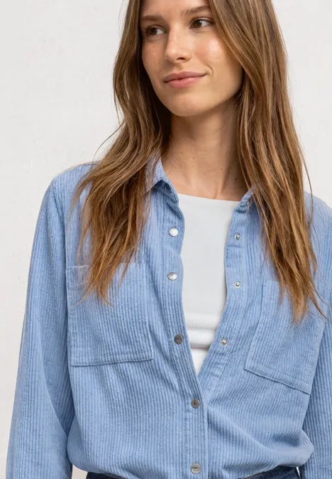 Corduroy overhemd met lange mouwen en knopen northern blue Junge Frau in hellblauem Jeanshemd über weißem Top, leicht lächelnd vor neutralem Hintergrund.