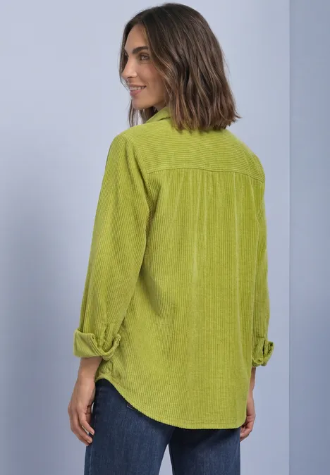 Corduroy overhemd met lange mouwen en knopen apple lime Frau im Rückenansicht trägt ein hellgrünes Cordhemd mit aufgekrempelten Ärmeln und Jeans.