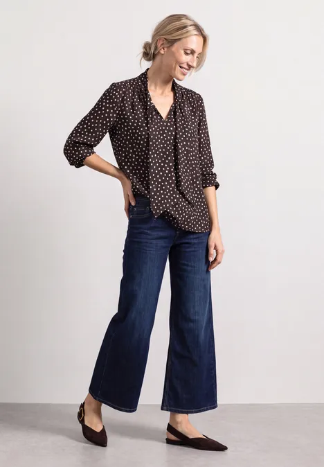 Langarm Bluse mit Schleifendetail black coffee Frau in gepunkteter Bluse, weiten cropped Jeans und flachen Schuhen.