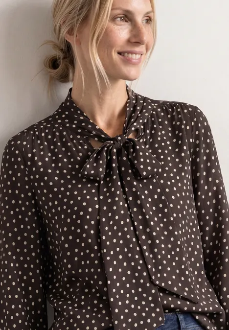 Langarm Bluse mit Schleifendetail black coffee Blonde Frau in brauner Bluse mit weißem Herzmuster und Schleife am Kragen, lächelnd zur Seite blickend.