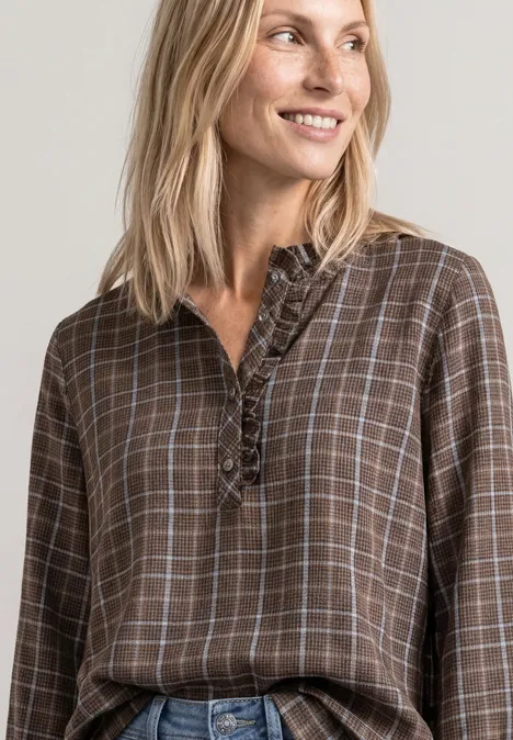 Langarm Bluse mit Rüschendetails silk brown Blonde Frau lächelt seitlich, trägt braun-kariertes Blusenshirt mit Rüschen vor neutralem Hintergrund.