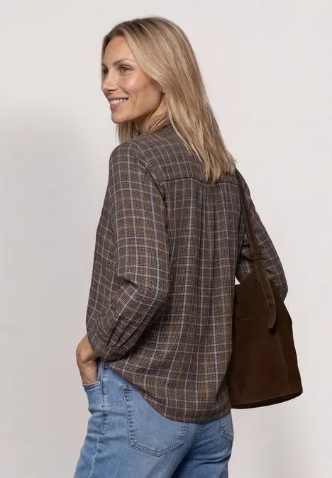 Langarm Bluse mit Rüschendetails silk brown Frau mit blonder Mähne trägt kariertes Hemd, Jeans und eine braune Schultertasche, lächelt seitlich.