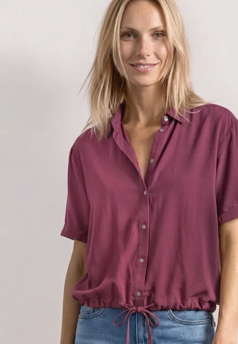 Overhemd met korte mouwen in effen kleur dark clouded blush Frau in magentafarbenem, kurzärmeligem Hemd mit Tunnelzug an der Taille, lächelnd vor hellem Hintergrund.