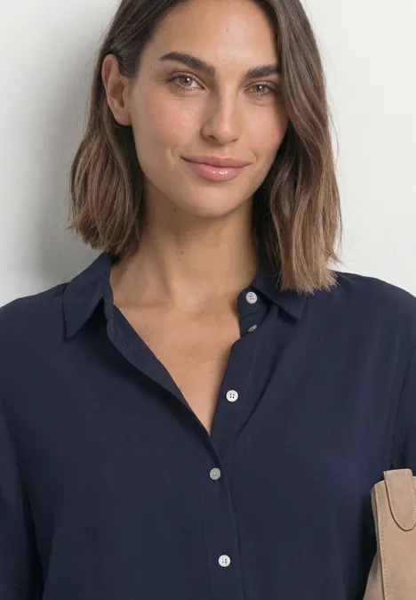 Overhemd met korte mouwen in effen kleur darkest blue Porträt einer Frau mit mittellangen dunklen Haaren in einer dunkelblauen Bluse vor hellem Hintergrund.