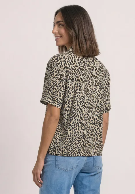 Kurzarm Hemdbluse mit Print cotton beige Frau mit beigeschwarzer, kurzärmliger Leo-Bluse und blauer Jeans, seitlich lächelnd.