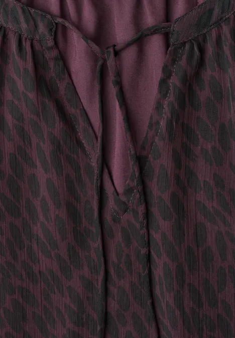Violett-schwarze gemusterte Bluse mit V-Ausschnitt und Stoffband zum Schnüren.