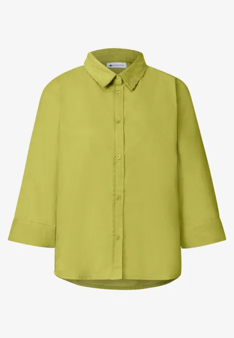 Eine hellgrüne, langärmelige Bluse mit Kragen und durchgehender Knopfleiste.