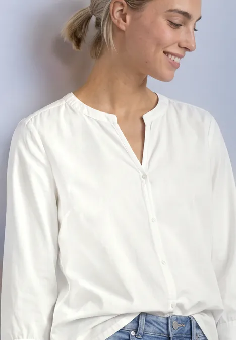 Blouse met 3/4-mouwen en split in de hals off white Eine lächelnde Frau trägt eine weiße Bluse mit Knopfleiste und Jeans.