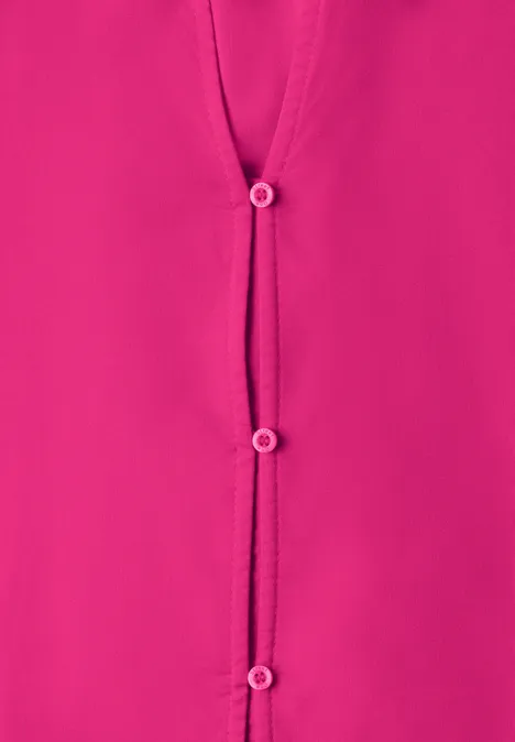Nahaufnahme einer pinkfarbenen Bluse mit drei Knöpfen.