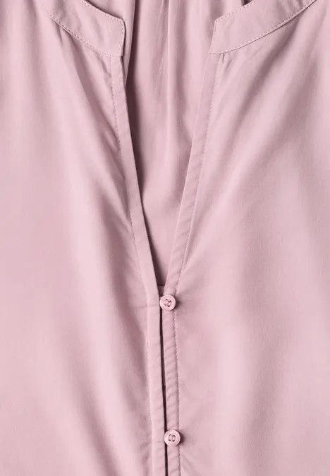 Gros plan d'un chemisier rose avec col, poches et boutons