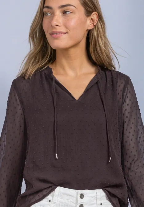 Chiffonblouse met split in de hals en bandjes ruby vine Vrouw in donkerbruin bloesje met doorzichtige stippenmouwen en koordsluiting bij de V-hals.
