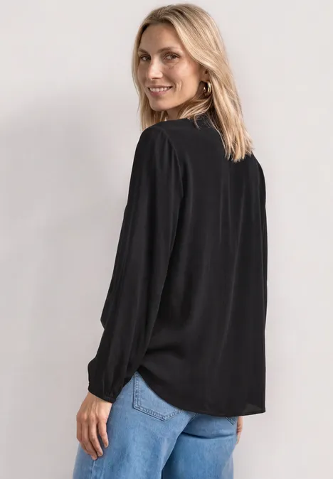Langarm Bluse mit Schleifendetail Black Frau von hinten in einer schwarzen Bluse mit Zierperlen und blauen Jeans