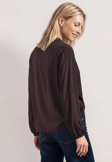 Blouse met lange mouwen en strikdetail ruby vine Frau von hinten in schwarzer Bluse und Jeans, lange Ärmel, lockere Passform.
