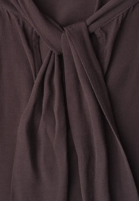 Blouse met lange mouwen en strikdetail ruby vine Nahaufnahme eines dunklen braunen Stoffs mit Knoten und sanften Falten.