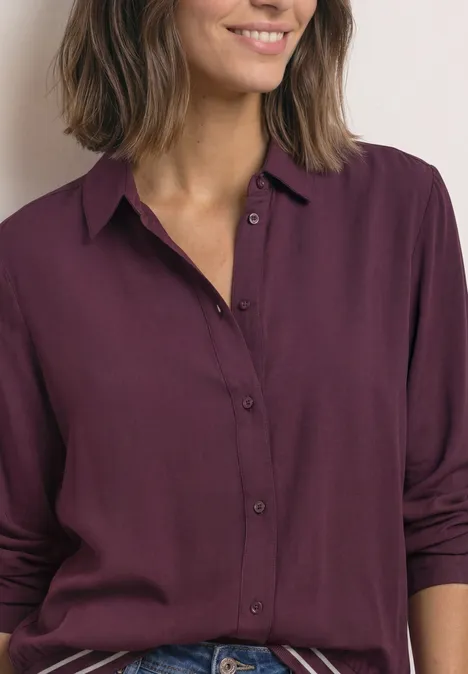 Overhemd met lange mouwen en elastische zoom rustic rouge Frau trägt eine dunkelviolette, langärmlige Bluse mit offenem Kragen vor hellem Hintergrund.