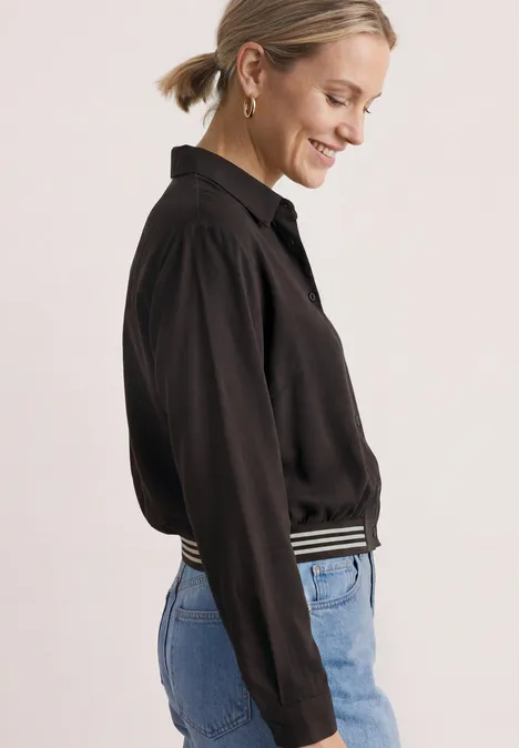 Overhemd met lange mouwen en elastische zoom black coffee Seitlich abgebildete Frau mit schwarzer Bluse und Jeans, lächelnd.
