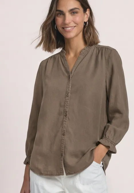 Blouse met 3/4-mouwen, split in de hals en ruches saddle brown Frau trägt lässige braune Bluse mit Knopfleiste und weiße Hose, lächelnd und entspannt.