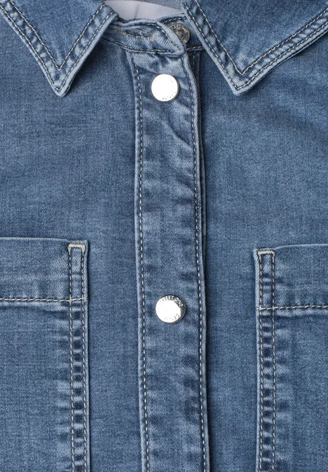 Overhemd met lange mouwen en borstzakken Medium Blue Soft washed Nahaufnahme einer blauen Jeansjacke mit Kragen, weißen Druckknöpfen und zwei Brusttaschen.